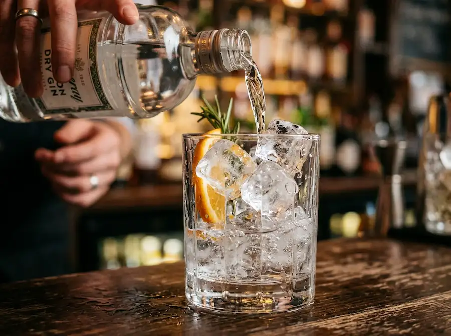 Pouring gin into a glass filled with ice